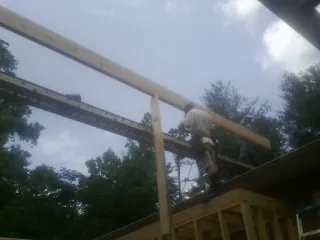 Carpenter setting a ridge beam over a new addition frame — Ice Dam Removal by Roofing Brothers in Cornelia