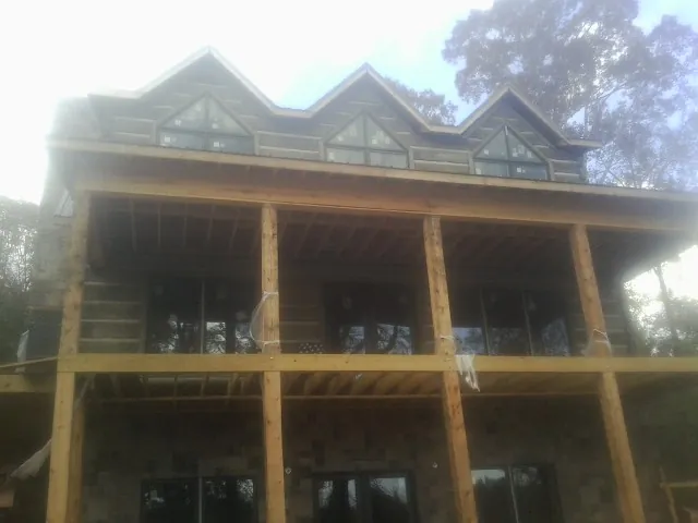 Dormers and porch framing on a large log home under construction — Roof Coating work by our crew in Cornelia