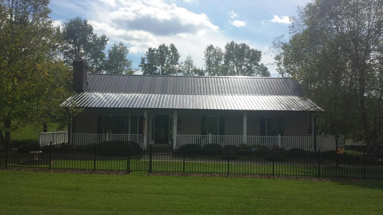 Gray metal roof on a brick ranch with a full width front porch — Gutter Guard Installation work by our crew in Cornelia